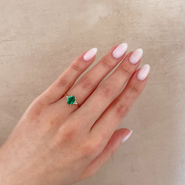 Alternative view of Close-up of a hand wearing the Dewlight Emerald Engagement Ring in 14k white gold, on a polished band.