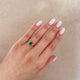 Close-up of a hand wearing the Dewlight Emerald Engagement Ring in 14k white gold, on a polished band.