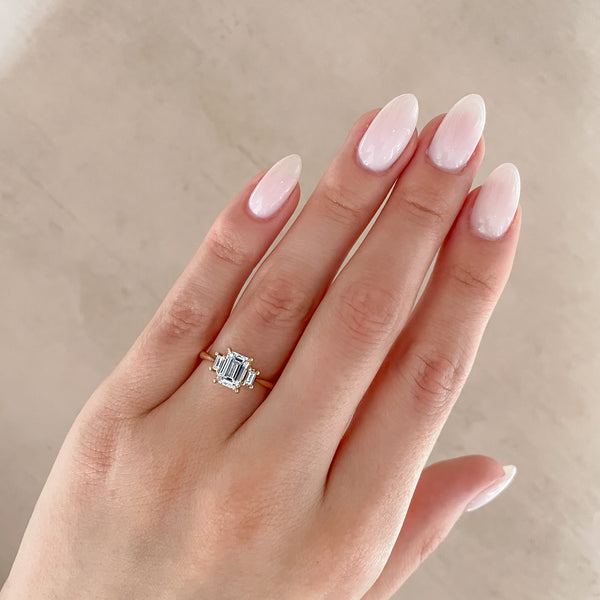 Alternative view of Close-up of a hand wearing the Hero Emerald Cut Three Stone Diamond Engagement Ring in 14k solid gold.