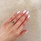 Close-up of a hand wearing the Love is All Emerald Engagement Ring in 14k solid gold, on a polished band.