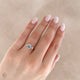 Close-up of a hand wearing the You, Me & Magic Round Cut Three Stone Engagement Ring in 14k white gold, on a polished band.