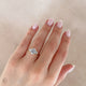 Close-up of a hand wearing the You, Me & Magic Round Cut Three Stone Engagement Ring in 14k white gold, on a polished band.